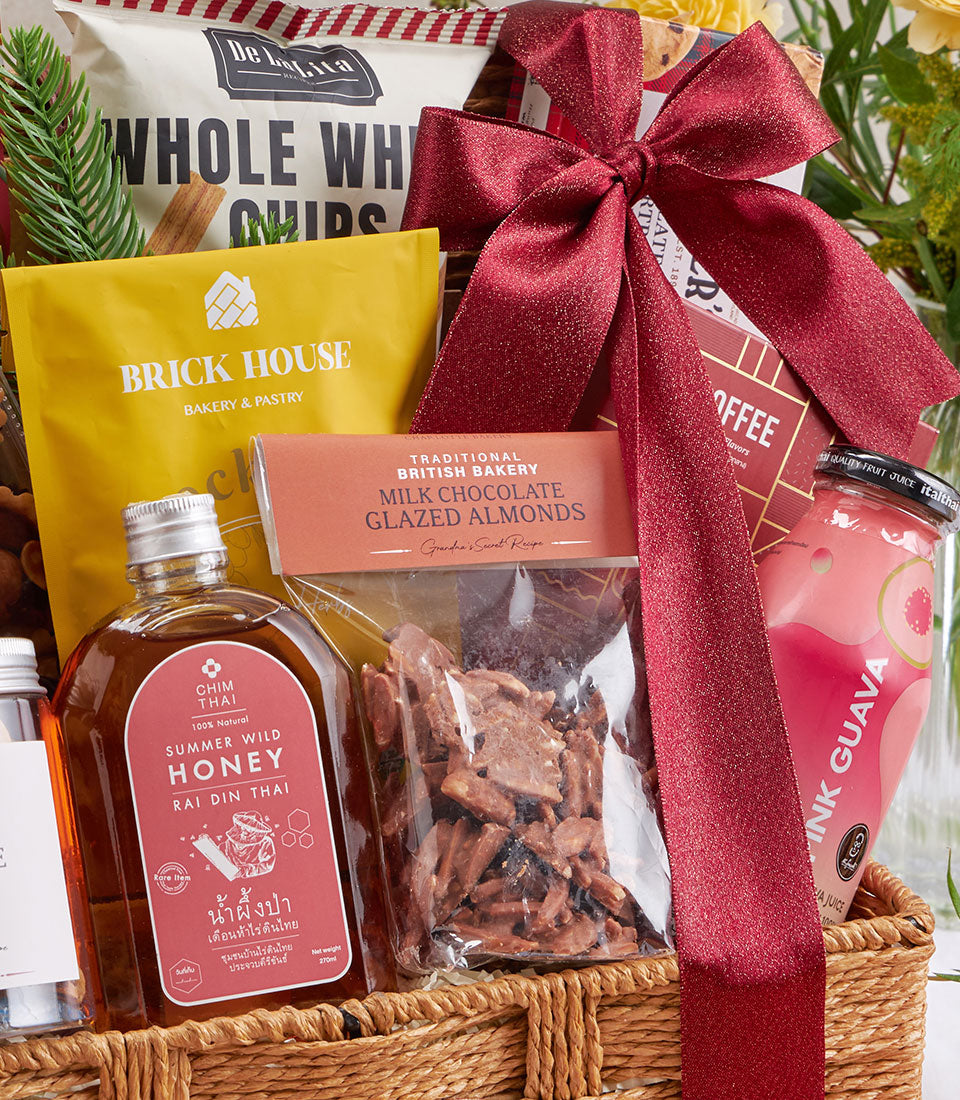 Woven gift basket filled with gourmet olive snacks, artisan cookies, wild honey, chocolate almonds, and premium treats with