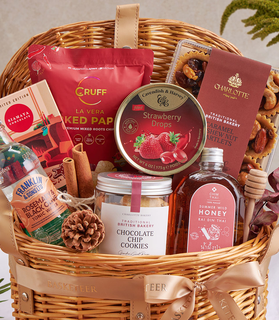 Woven wicker gift basket with chocolate chip cookies, honey, gourmet treats, and artisan confections tied with gold ribbon