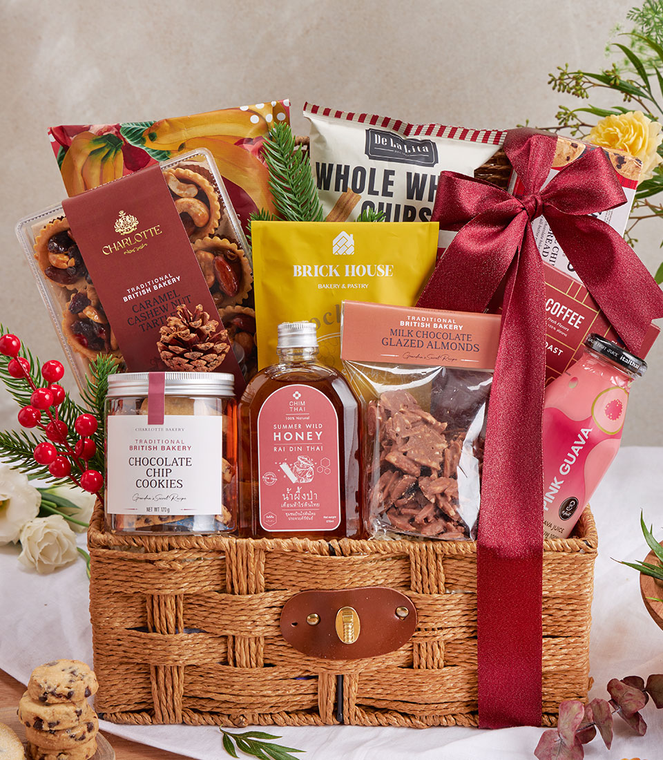 Woven gourmet gift basket with olive snacks, cookies, honey, almonds, and artisan treats tied with burgundy ribbon