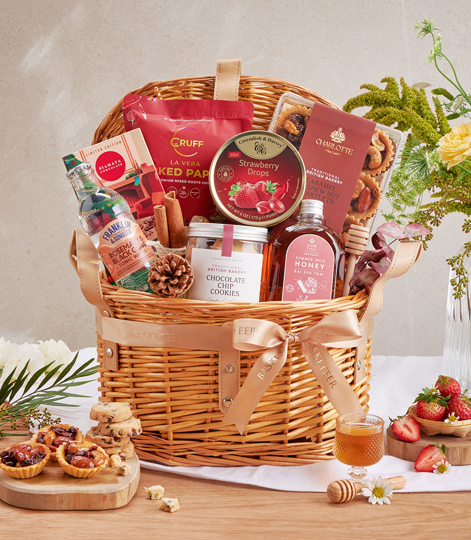 Gourmet chocolate chip cookies, honey, and artisan treats in wicker basket with tan leather straps