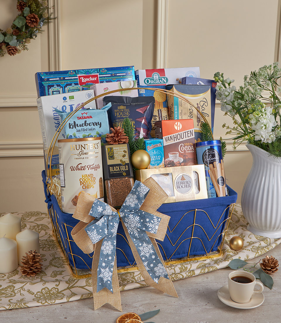 Royal blue gourmet gift basket with festive snowflake ribbon, filled with artisan snacks, chocolates, coffee and cocoa for