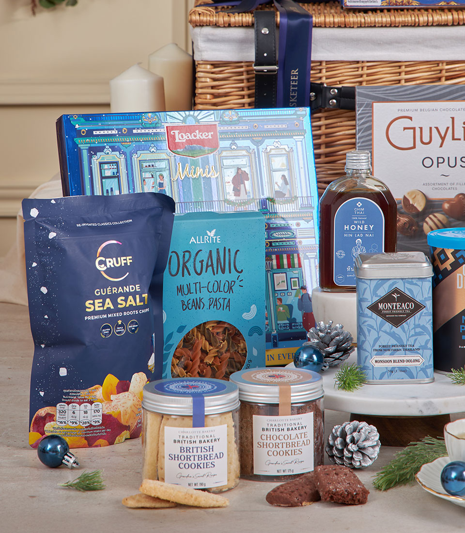 Blue wicker luxury gift basket with gourmet chocolates, premium tea, shortbread, and artisan treats for New Year gifting