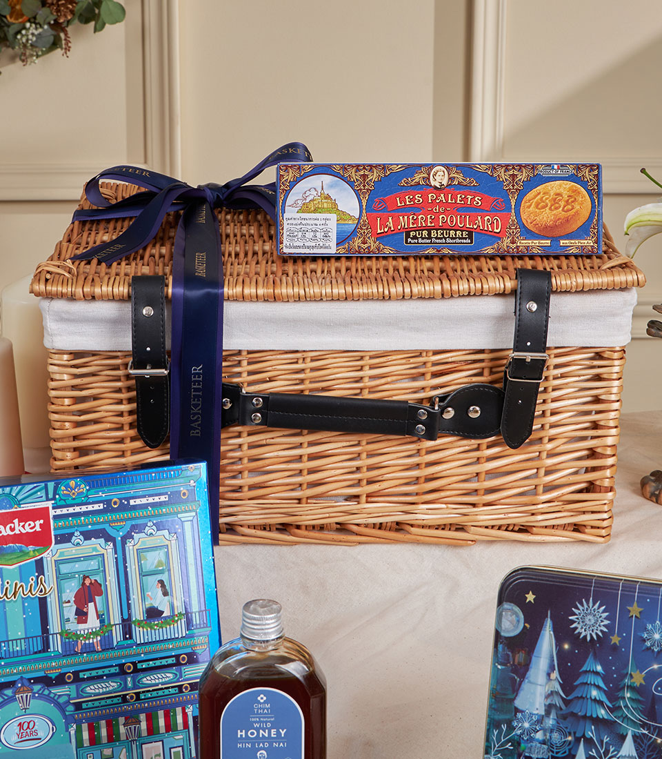 Blue winter luxury chocolate hamper with wicker basket, French shortbreads, honey, and festive treats for New Year gifting