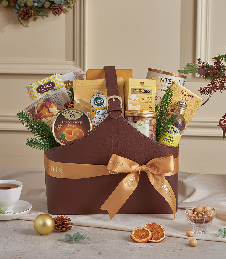 Golden faux leather gourmet gift basket with Earl Grey tea, Arabica coffee, chocolate, and artisan treats tied with gold