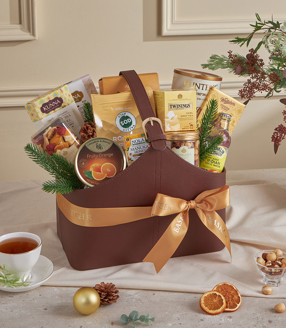 Dark brown leather gourmet gift basket with gold buckle, filled with premium coffee, tea, honey, and artisan treats for New