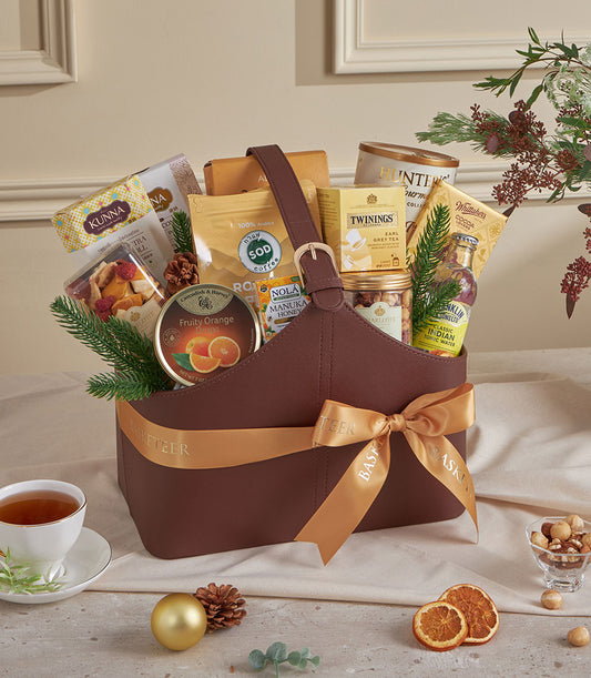Dark brown leather gourmet gift basket with gold buckle, filled with premium coffee, tea, honey, and artisan treats for New