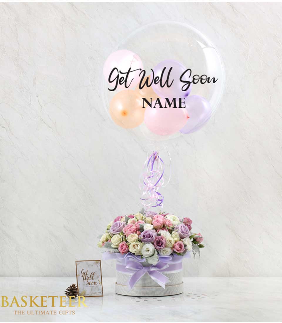 Purple and pink roses in lavender-ribboned hatbox with Get Well Soon bubble balloon combo