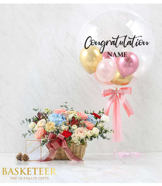 Vibrant mixed rose and hydrangea bouquet in woven basket with congratulations balloon and ribbon bow