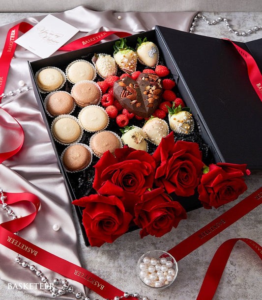 Luxe Valentine's gift set with red roses, macarons, chocolate heart, and strawberries in black box