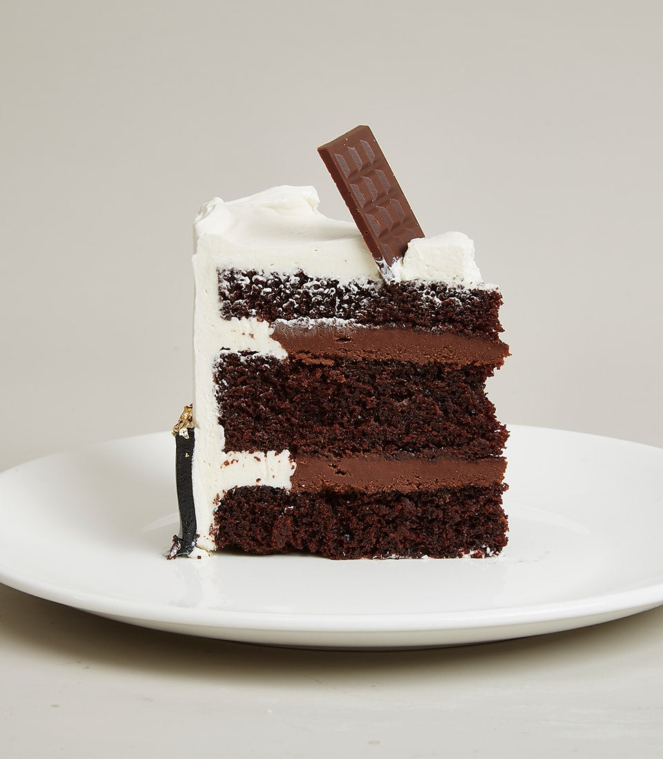 Layered chocolate cake with white frosting and gold leaf detail, mini celebration cake by Charlotte Bakery