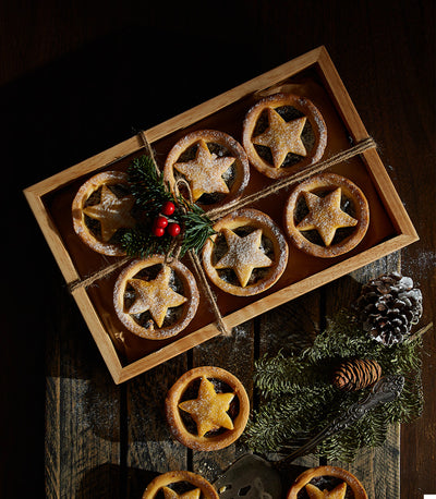 Starlight Mince Pies with star-shaped pastry tops, dusted with powdered sugar, arranged in wooden tray with festive pine and