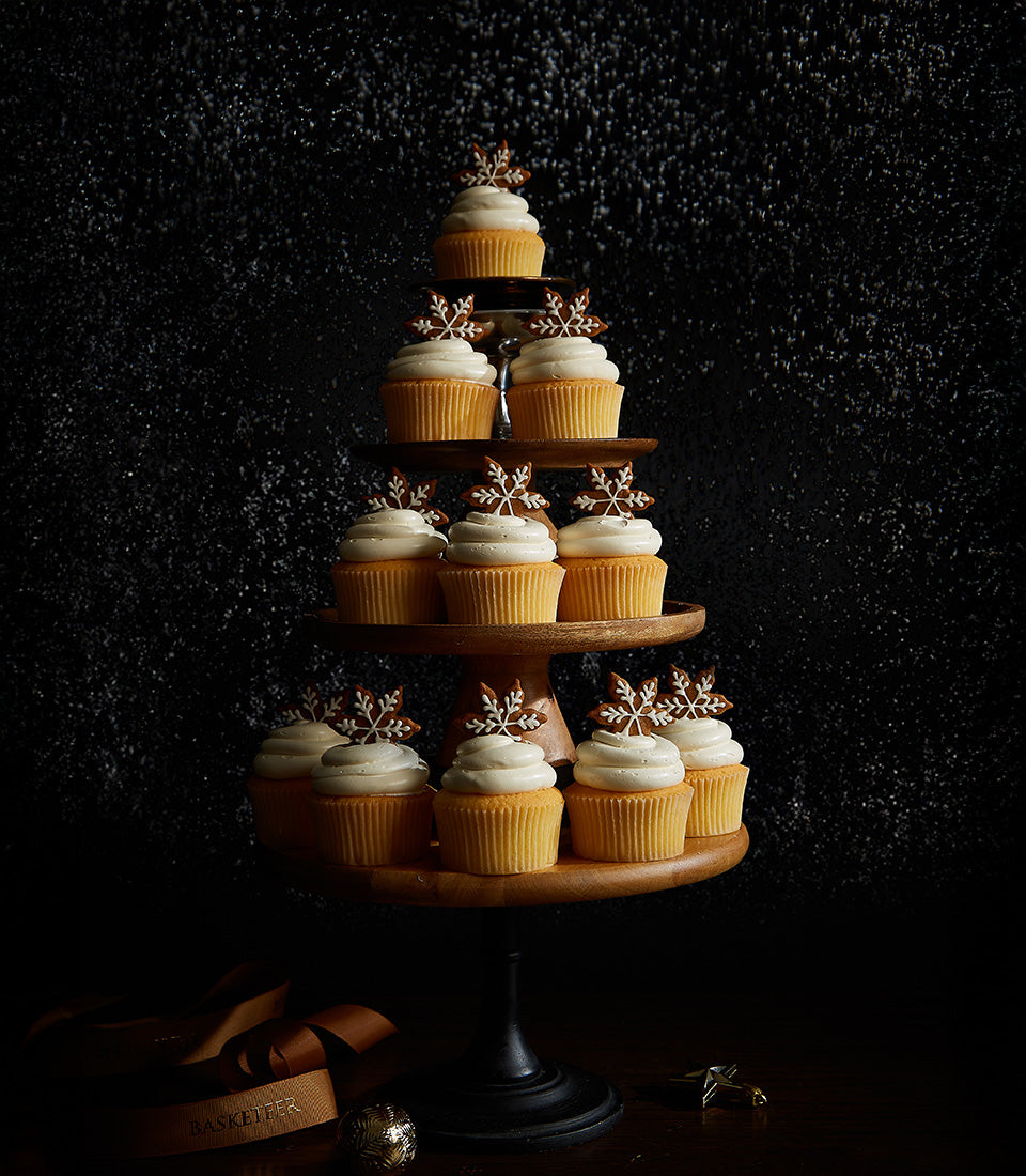 Biscoff cream white frosting cupcakes with gingerbread snowflake toppers arranged in Christmas tree shape