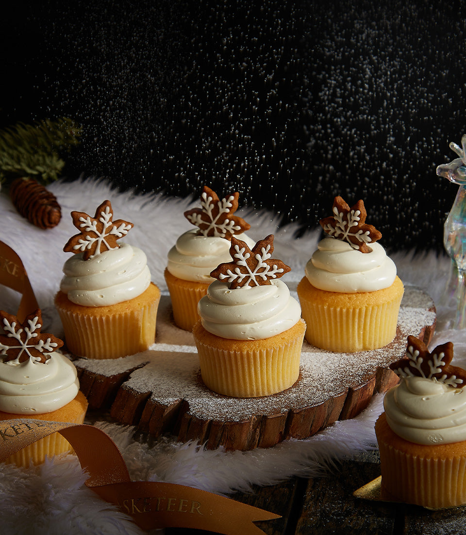 Christmas vanilla cupcakes with white frosting and gingerbread snowflake cookies on wooden slab