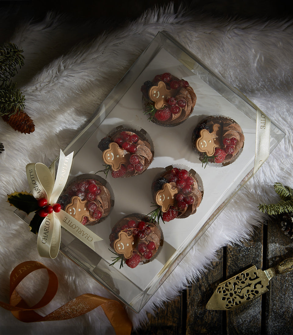 Chocolate ganache cupcakes with gingerbread man cookies, red currants, and rosemary in festive gift box
