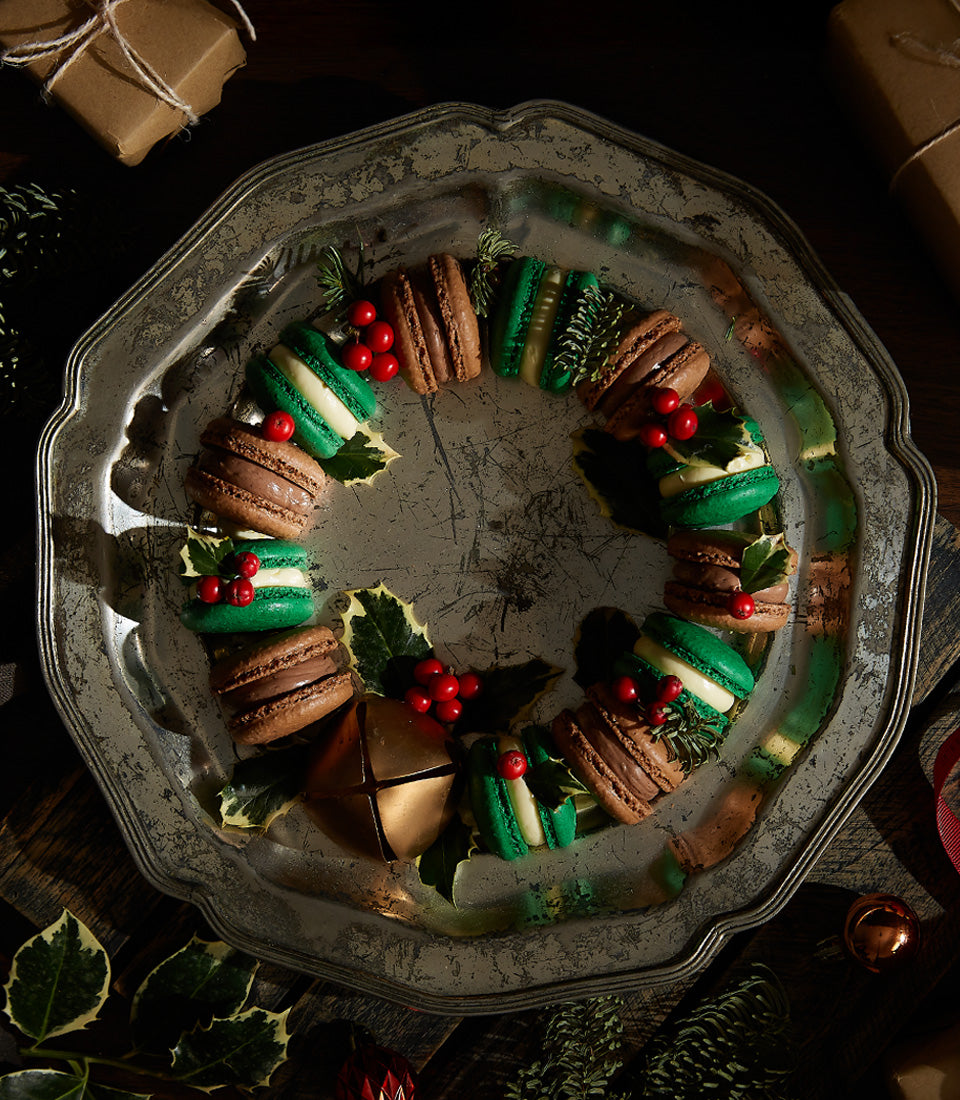 Christmas macaron wreath with amaretto and brandy cream flavors, green and chocolate macarons with holly and berries on