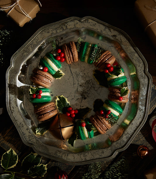 Christmas macaron wreath with amaretto and brandy cream flavors, green and chocolate macarons with holly and berries on