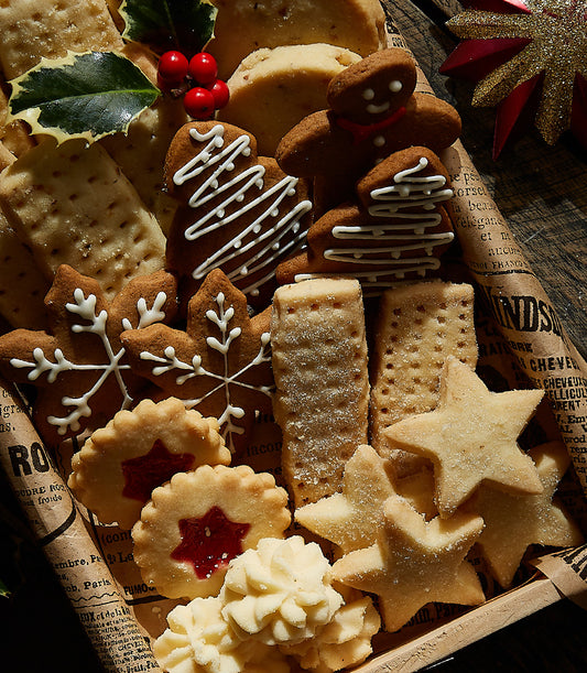 Festive Christmas cookie assortment with gingerbread, snowflake shortbread, and jam-centered treats in rustic wooden tray