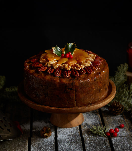 Traditional dark fruitcake with pecans, walnuts, and dried apricots, topped with holly and berries for Christmas