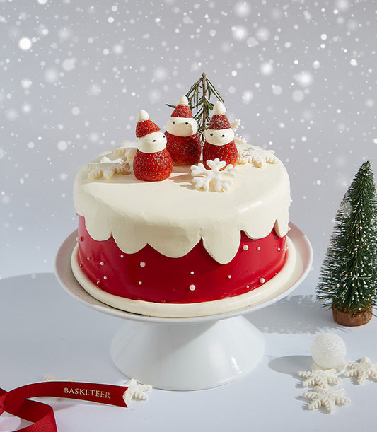 Festive red and white Christmas cake with strawberry Santas, snowflake decorations, and snowy frosting drip on cake stand