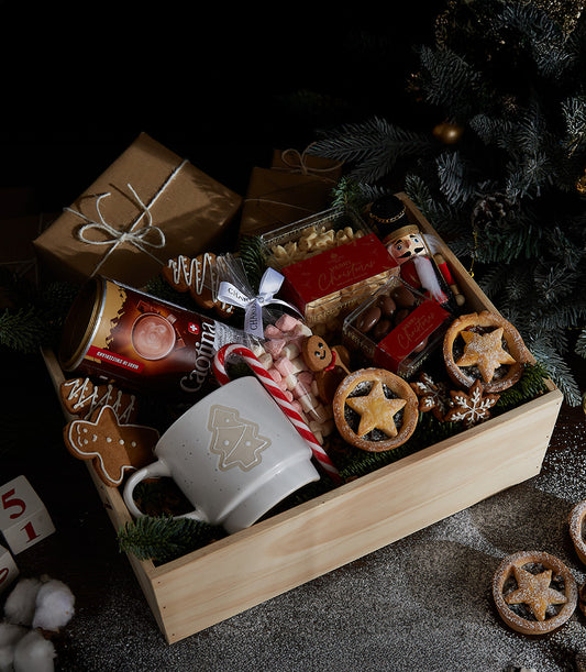 Wooden crate Christmas gift box with hot chocolate, festive mug, gingerbread, cookies, marshmallows and chocolate treats