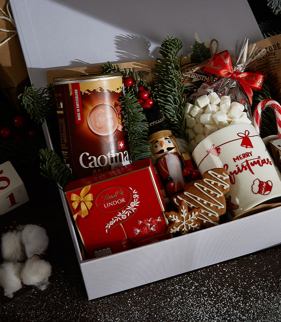 Festive Christmas gift box with hot chocolate, Lindor chocolates, marshmallows, mug, gingerbread cookies and holiday