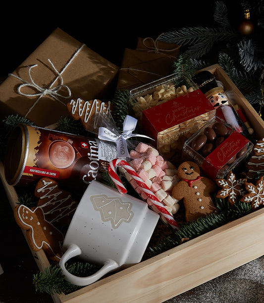 Festive Christmas gift crate with hot chocolate, mug, marshmallows, gingerbread cookies, and holiday treats