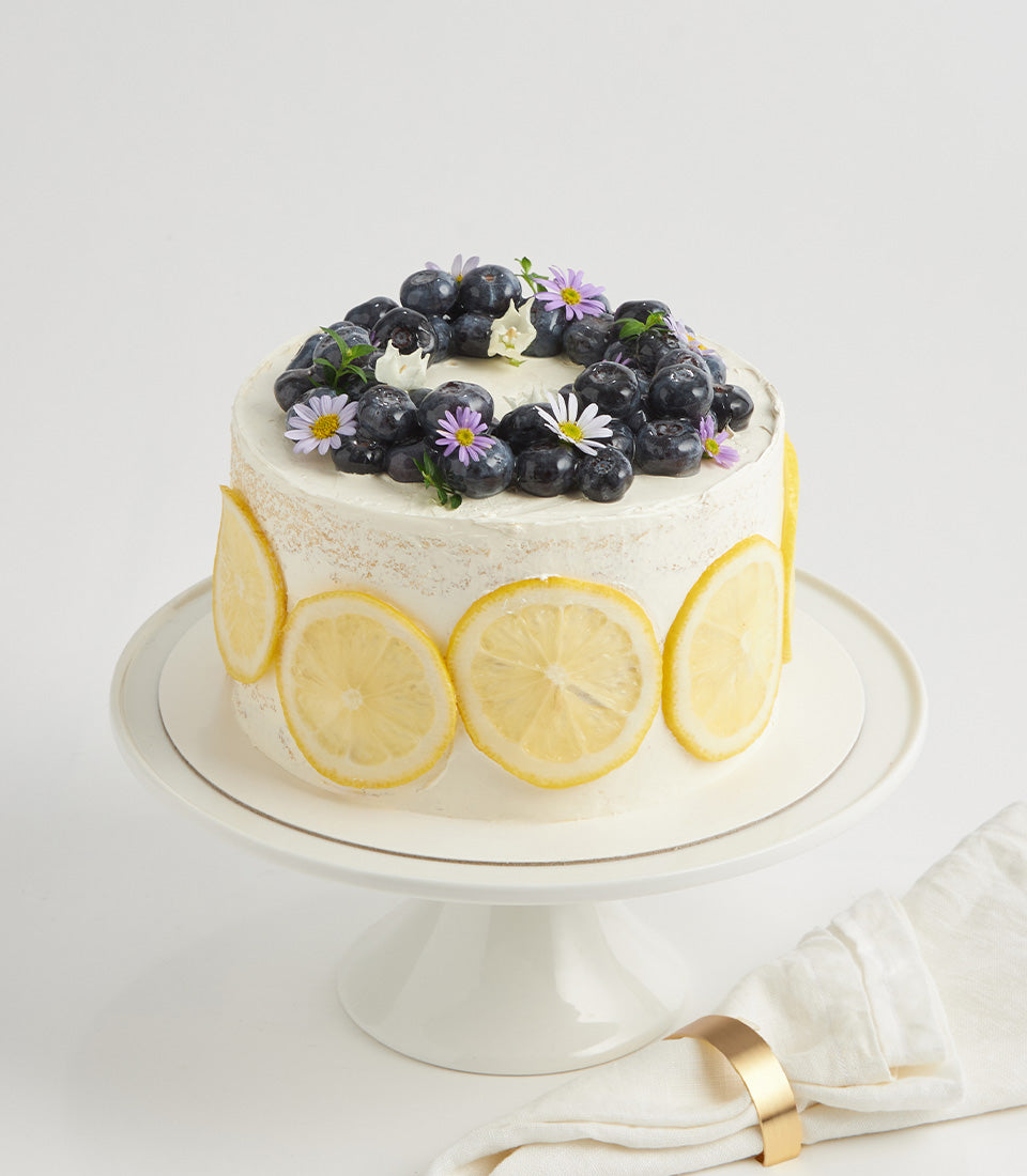 Lemon zest buttercream layer cake with fresh blueberries and purple flowers for birthday celebrations