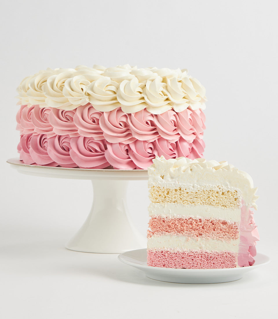 Charlotte Bakery custom cake Bangkok: Round artisan cake with pink ombre buttercream rosettes and a slice showing strawberry layers.