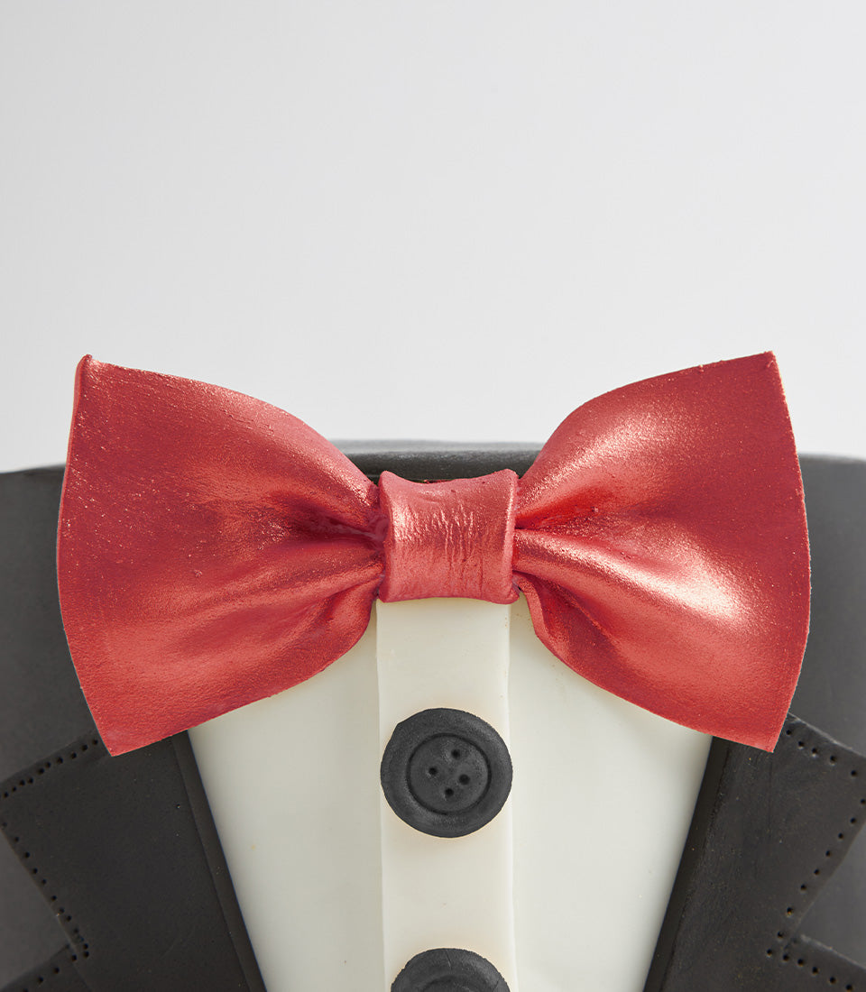 Black fondant tuxedo cake with metallic red bow tie and detailed jacket lapels