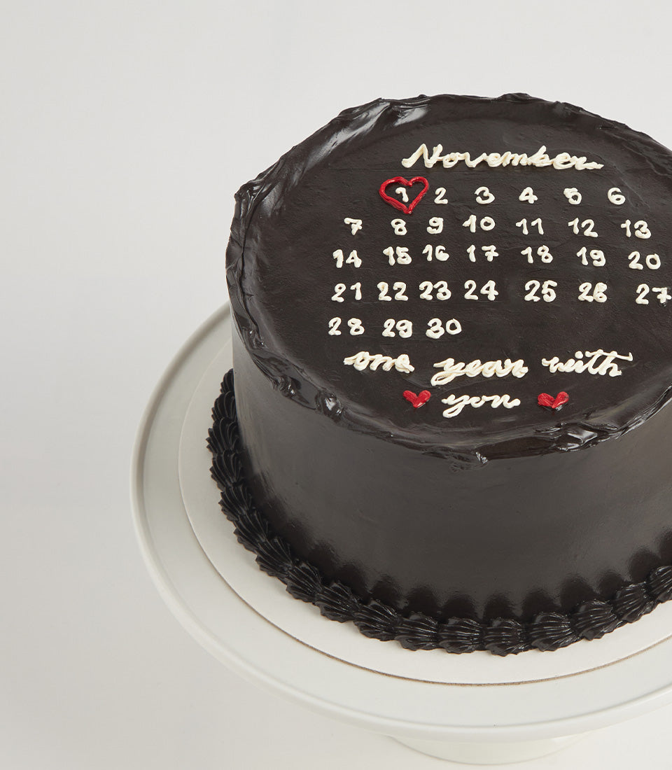 Dark chocolate anniversary calendar cake with white icing November design and red heart date marker