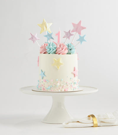 Pastel star two-tier birthday cake with fondant stars and sprinkles on white cake stand