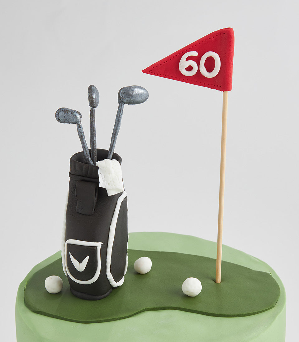 Custom golf-themed birthday cake with edible putting green, golf bag, clubs, and red flag topper