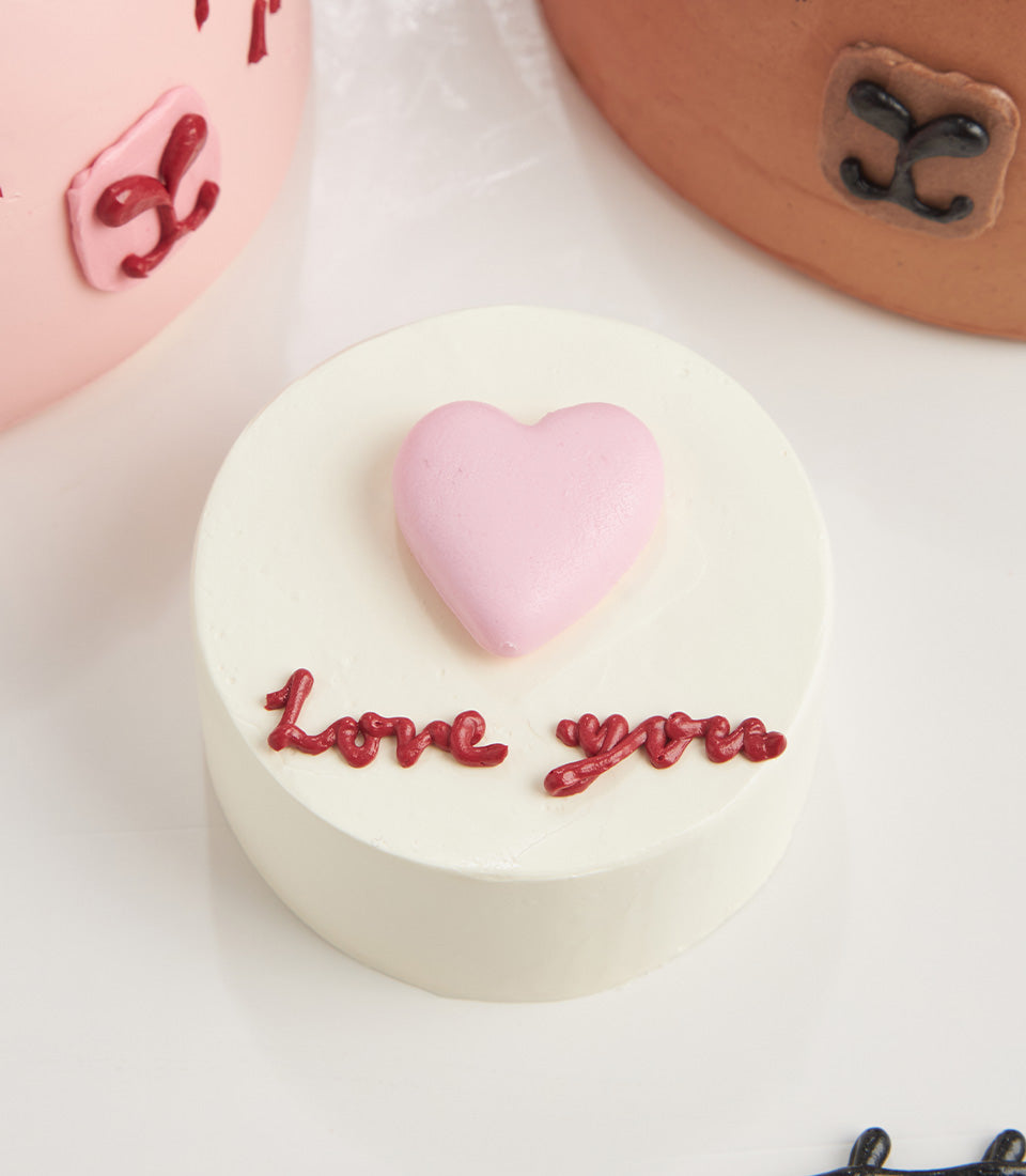 Petite white vanilla layer cake with pink fondant heart and "Love you" message in red icing