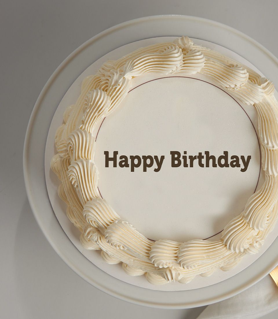 Classic cream birthday cake with "Happy Birthday" message and ruffled frosting border on white stand