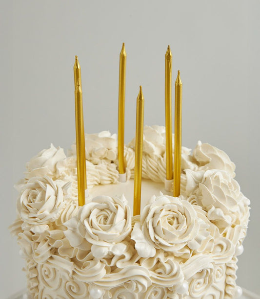 White buttercream celebration cake with gold candles and piped rosette details