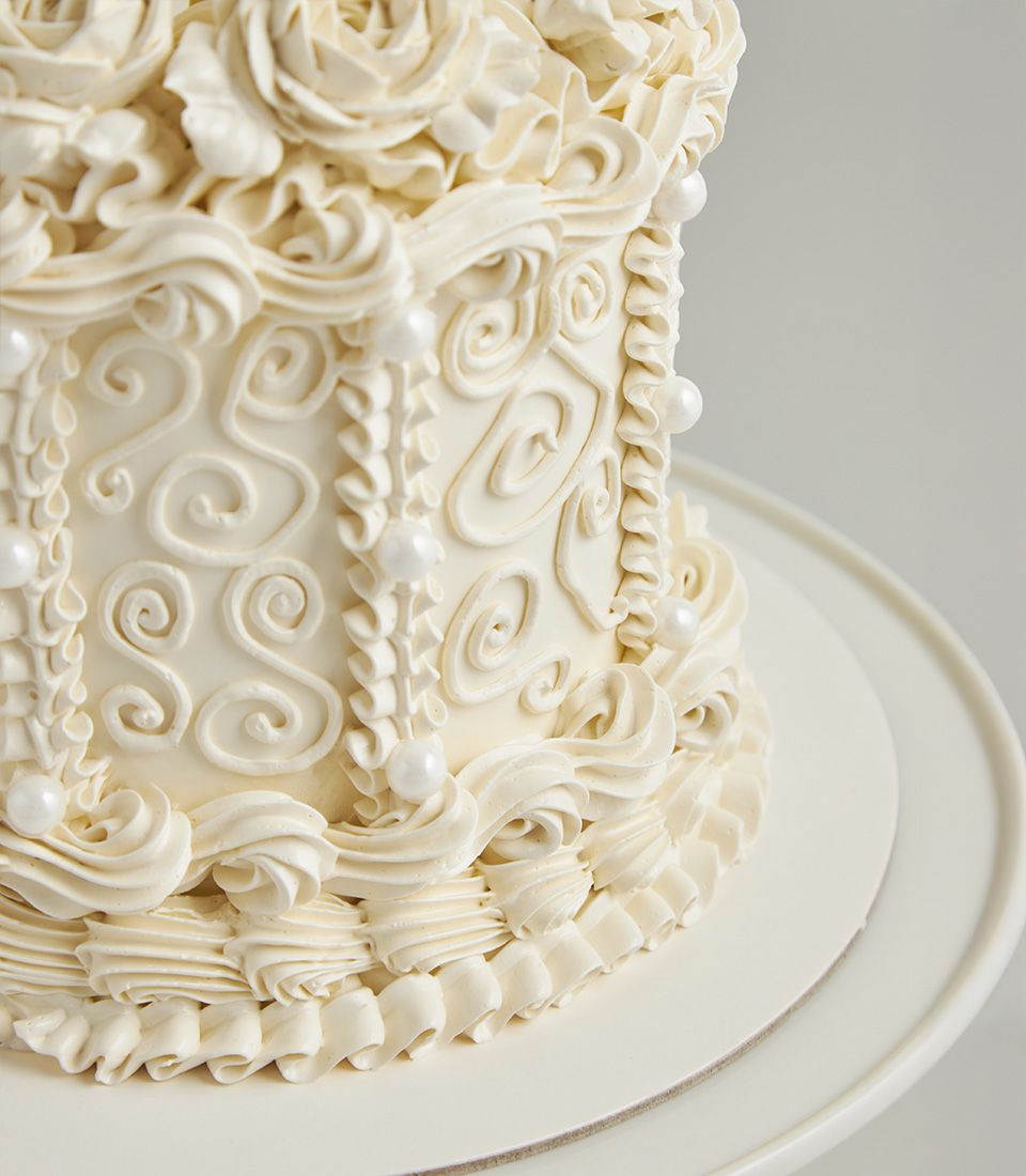 White buttercream celebration cake with vintage piping, ruffles, and basketweave detail