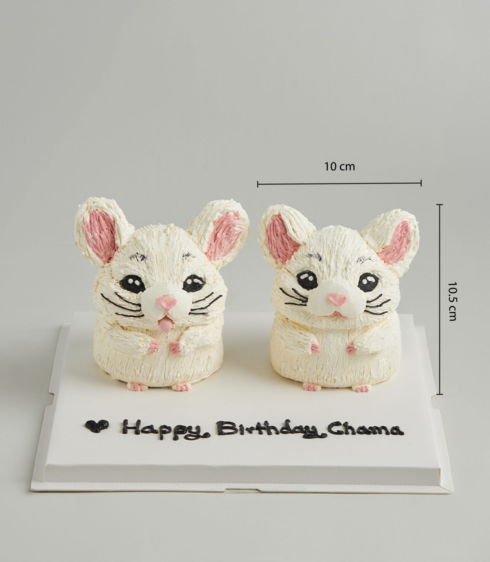 Twin white buttercream chinchilla cakes with pink ears and black frosting details, personalized birthday message on board