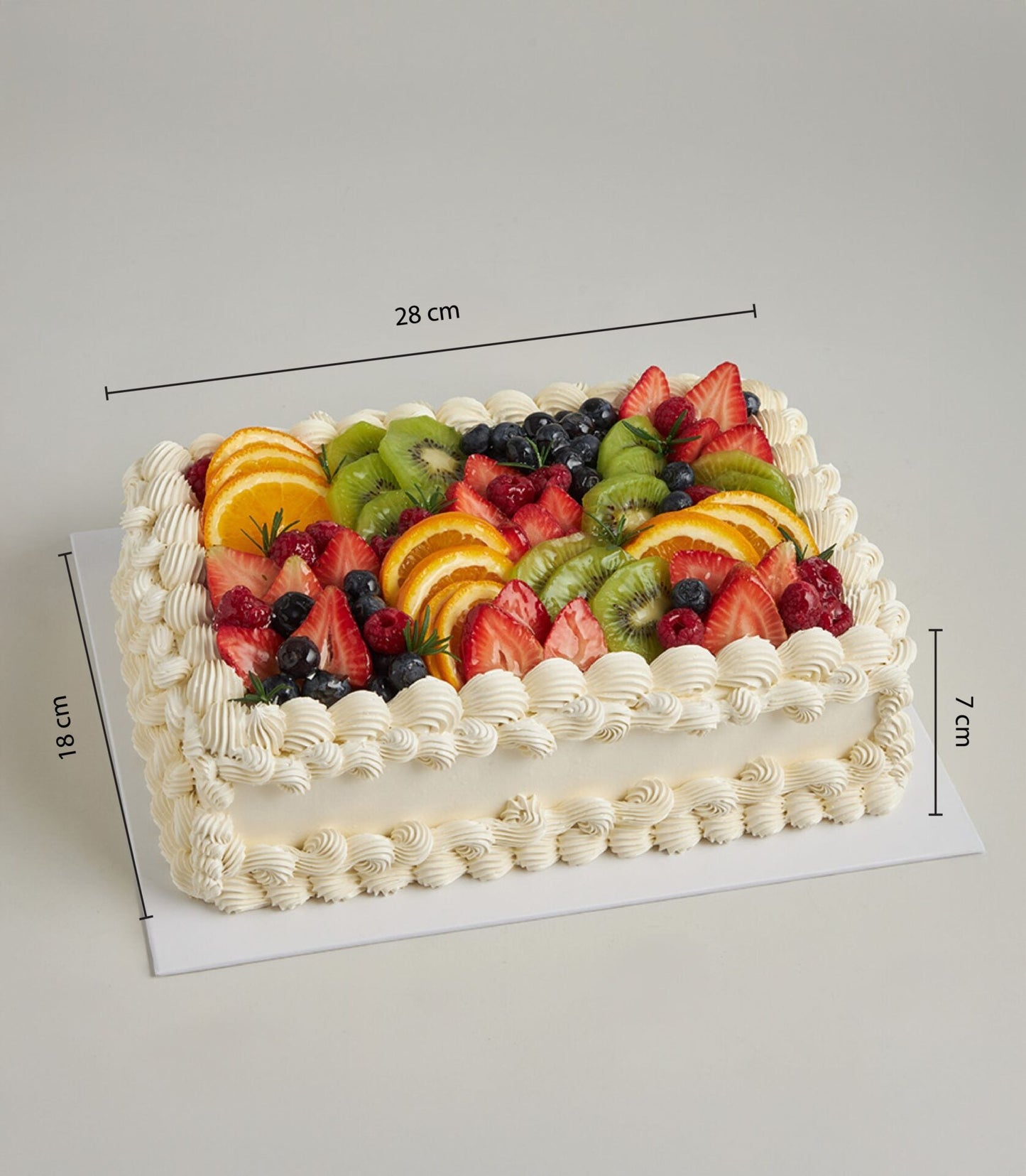 Rectangular cream-frosted celebration cake topped with fresh strawberries, kiwi, blueberries, and oranges for birthdays