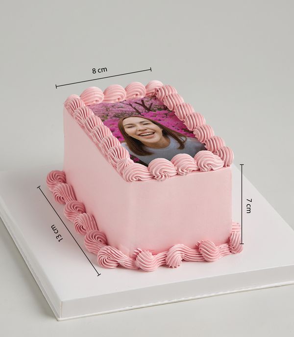 Pink buttercream layer cake with personalized edible photo and piped frosting swirls