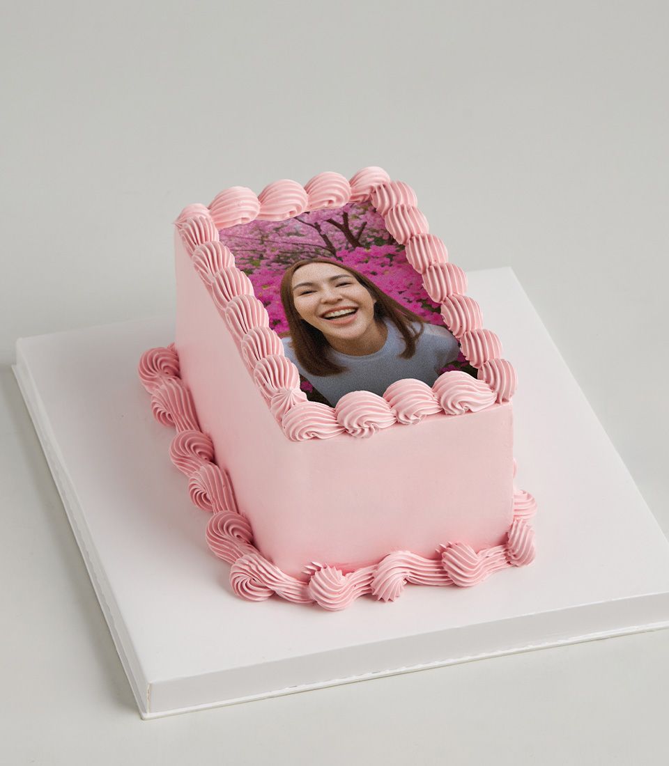 Pink buttercream layer cake with custom edible photo and piped frosting border