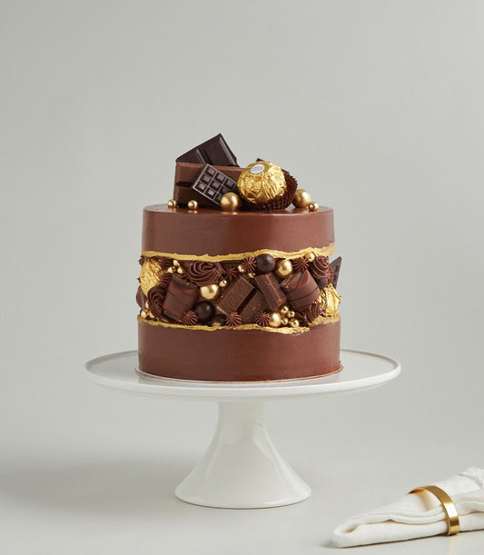 Luxury two-tiered chocolate ganache cake with Ferrero Rocher, gold leaf details, and artisan truffles