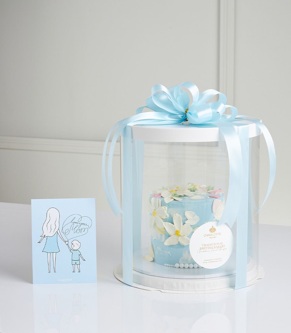 Light blue Mother's Day cake with white and pink florals, satin ribbon, and greeting card
