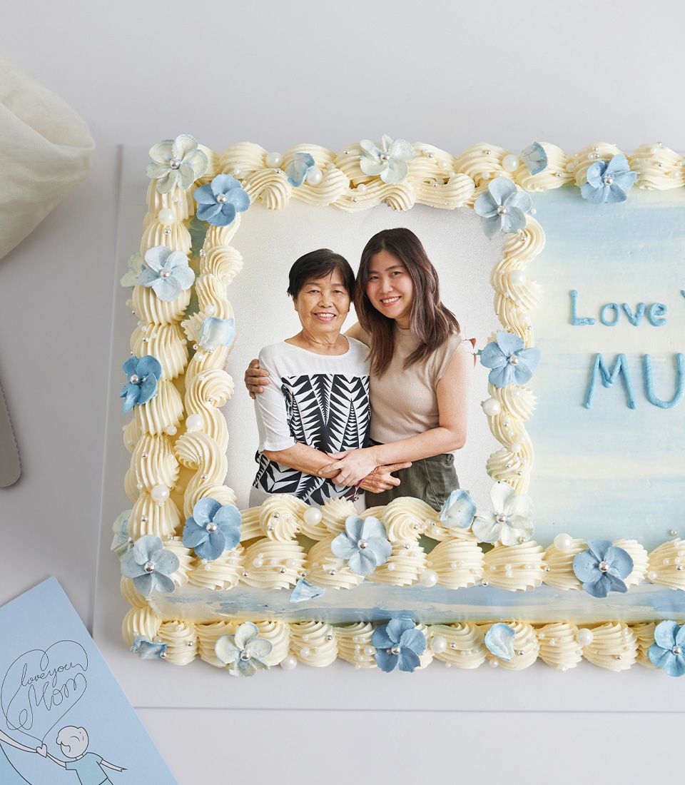 Light blue and white Mother's Day vanilla cake with edible photo of mother and daughter, piped frosting swirls, and "Love