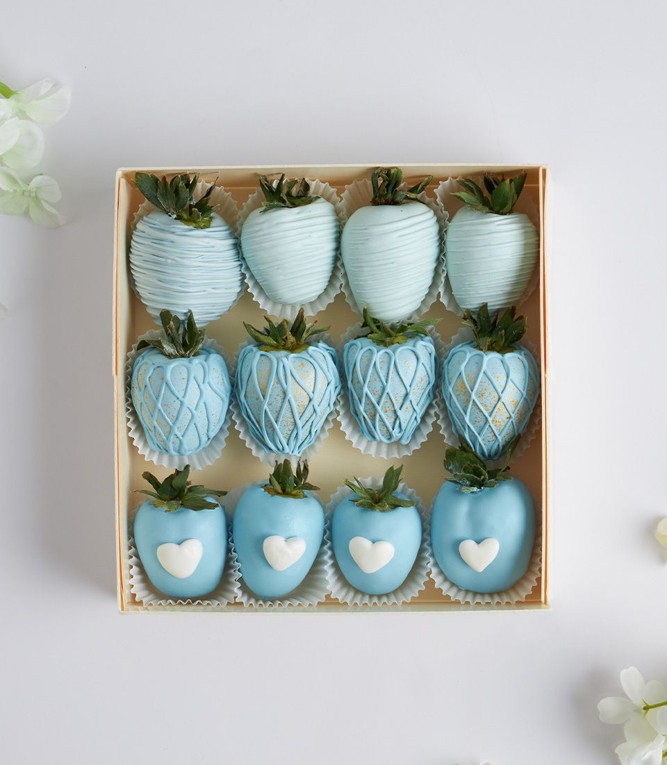 Twelve light blue chocolate-covered strawberries in decorative lattice and heart designs, gift-ready in fluted paper cups