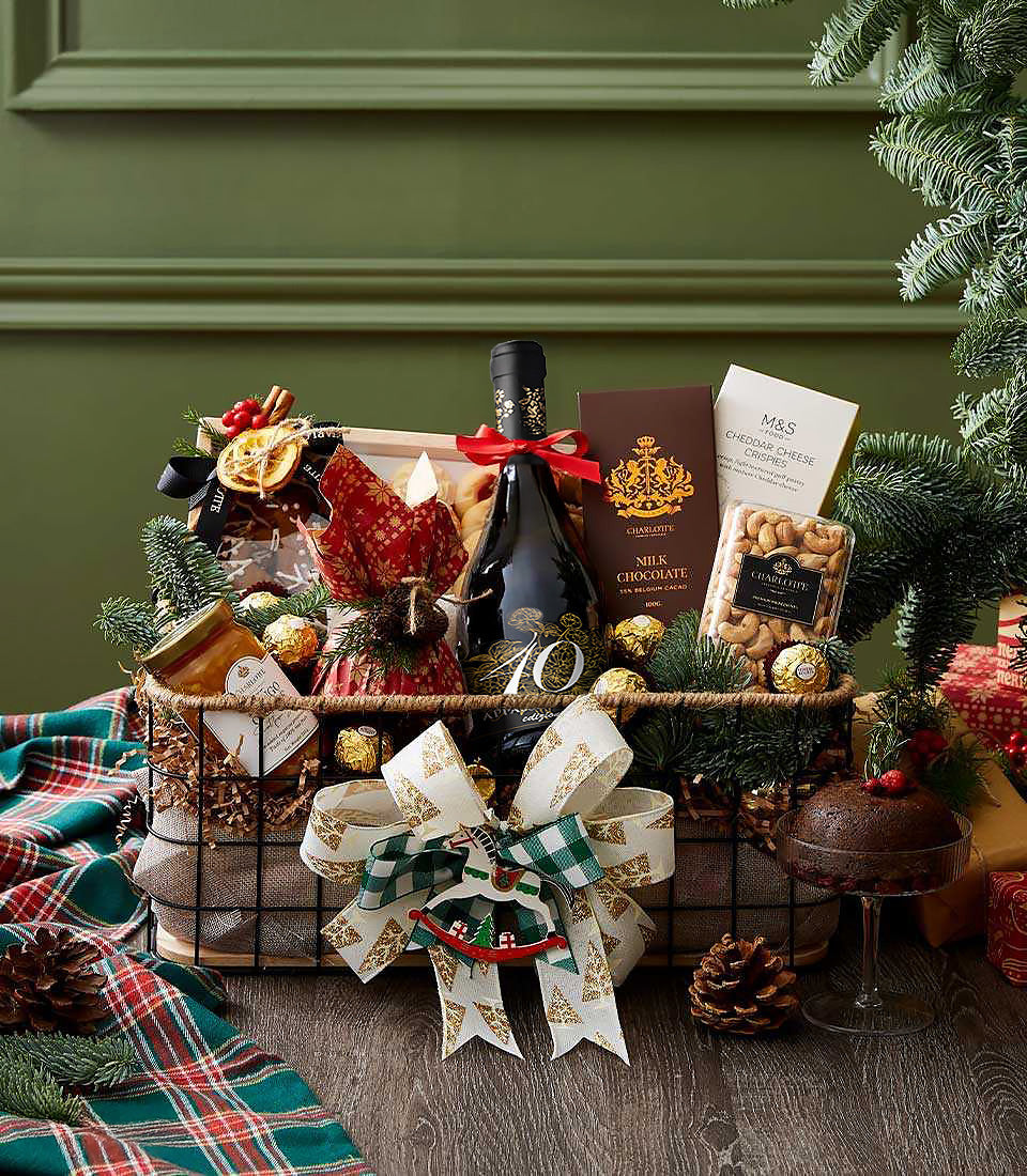 Festive red wine gift basket with champagne, chocolate, cheese crisps, and gourmet treats in dark wire basket