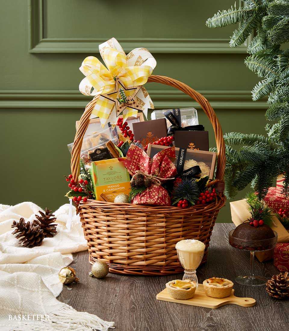 Festive Christmas hamper with gourmet treats, yellow gingham bow, and holiday greenery in woven wicker basket