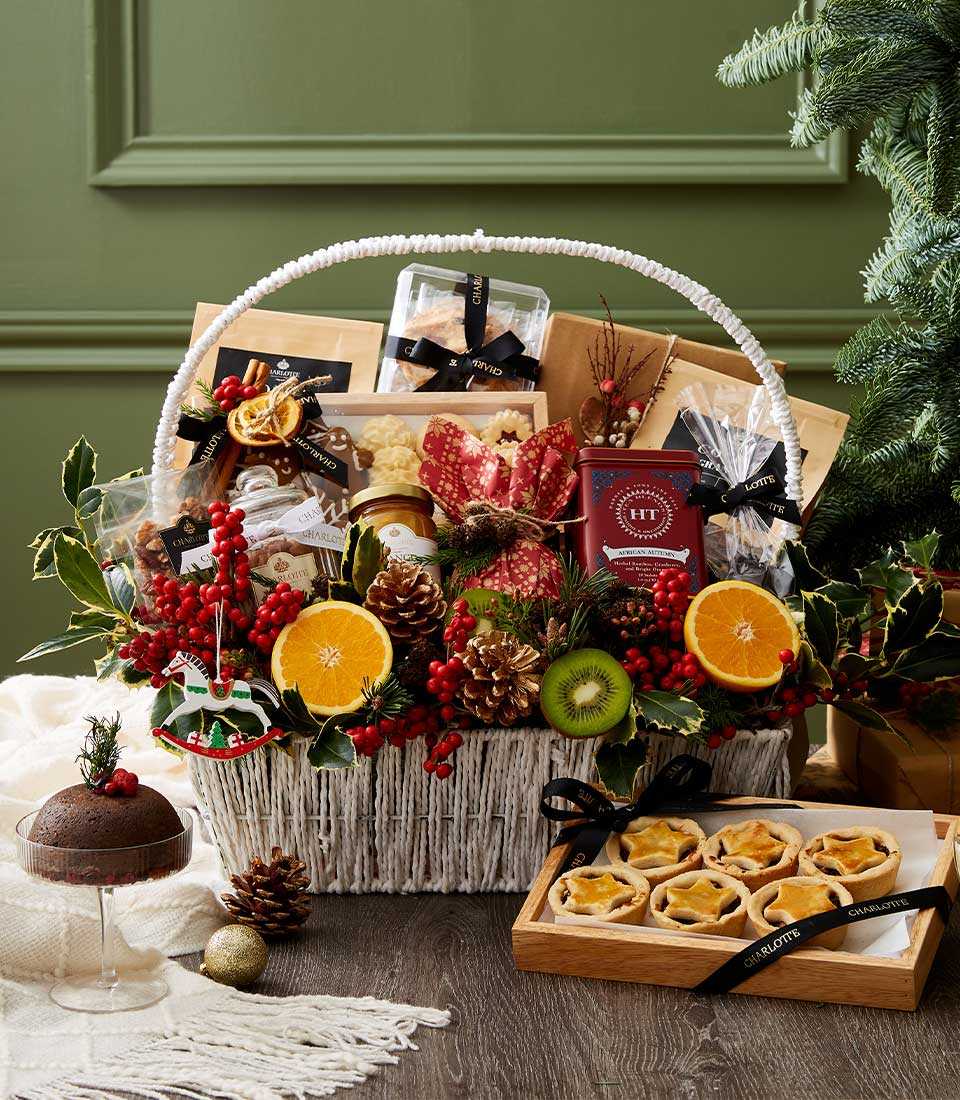 Luxe white woven Christmas gift basket with gourmet preserves, artisan cookies, and festive holly, paired with mince pies