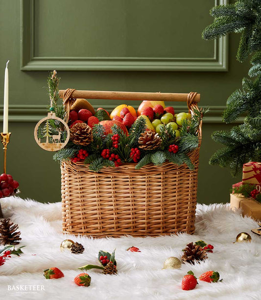 Festive Christmas fruit basket with strawberries, grapes, pears, oranges, pine branches and holiday decorations