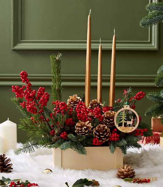 Festive Christmas pinecone and candle centerpiece with gold tapers, red berries, and gilded accents in wooden box