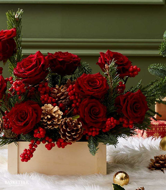 Deep red roses with pine, berries, and gold pinecones in wooden box Christmas arrangement